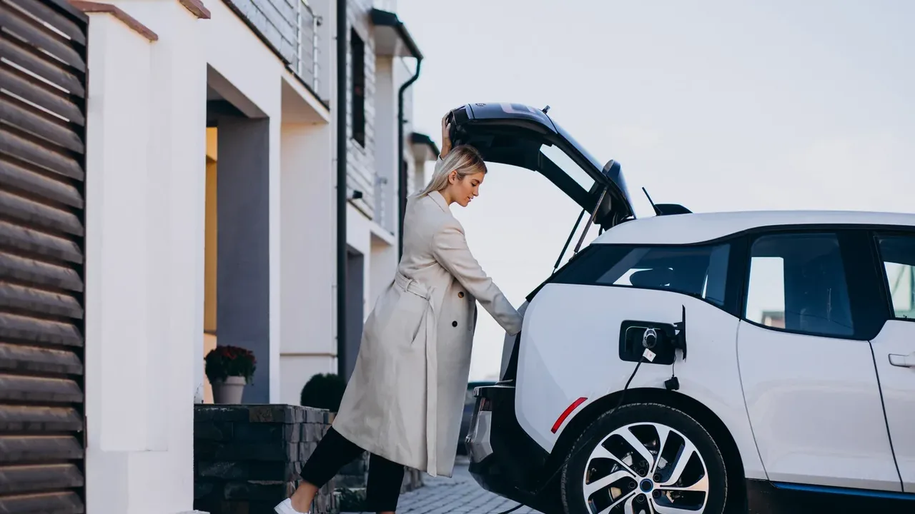 Evin önünde şarj kablosu bağlı elektrikli otomobil