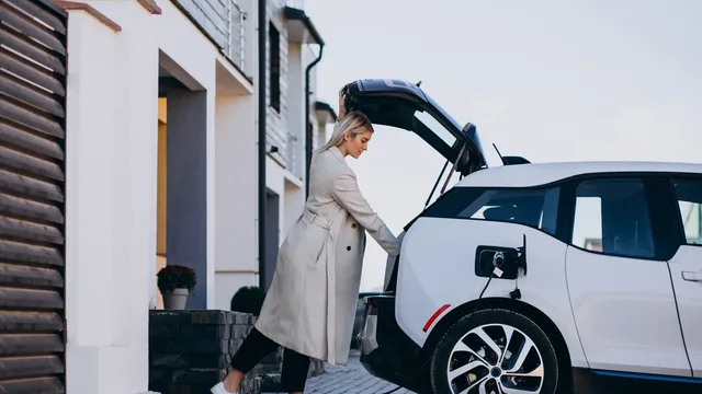 Evin önünde şarj kablosu bağlı elektrikli otomobil